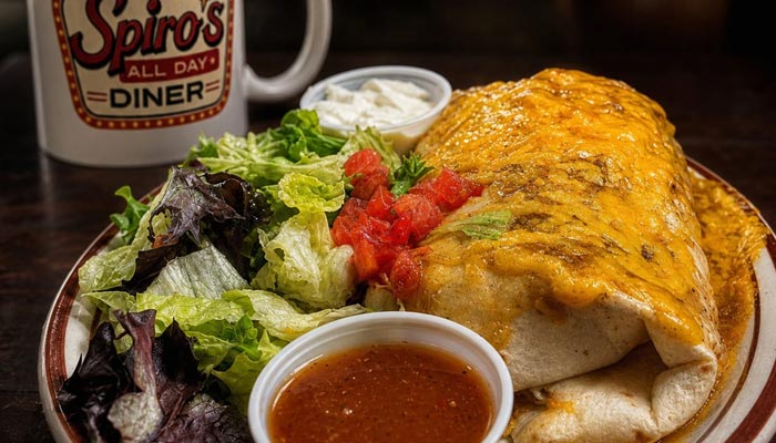Cheesy burrito with lettuce, tomatoes, sauces, and a coffee mug—see our Breakfast Menu Tooele UT.