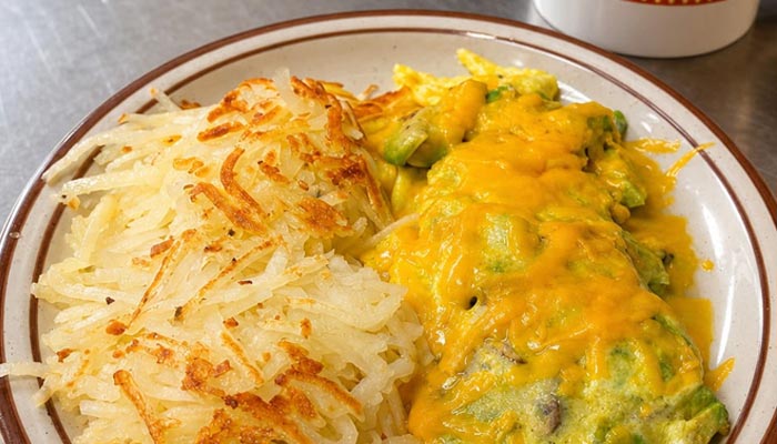 Enjoy our Breakfast Menu Tooele UT: hashbrowns and a cheesy omelet with avocado on a plate.
