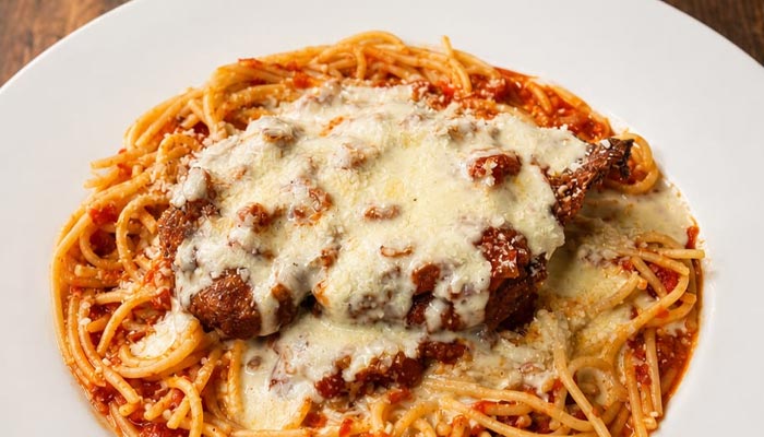 Enjoy our Lunch and Dinner Menu Tooele UT: spaghetti with breaded chicken, sauce, and cheese.