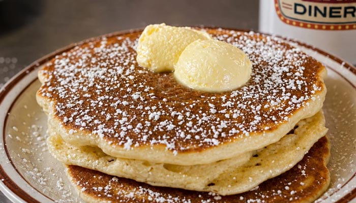 Two pancakes topped with butter and powdered sugar, a Breakfast Menu Tooele UT favorite.
